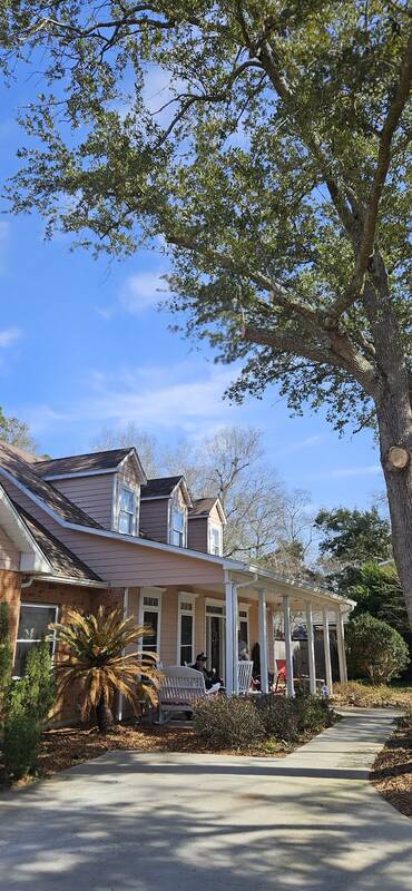 Trimmed oak over a two-story house with a long front porch and a concrete walkway
